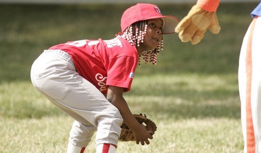 Taylor Paige Nevils of South Side Little League Memphis Red Sox from Chicago, peers up at Dugout, the Little League mascot, during a T-ball game on the South Lawn Sunday, June 26, 2005. White House photo by Paul Morse