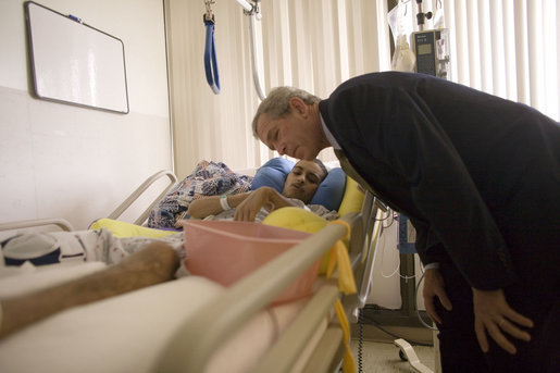 President George W. Bush leans down to Army Specialist Emmanuel Melendez-Diaz, as he asked the President for a special coin to send to the soldier who saved his life while serving in Operation Iraqi Freedom. Specialist Melendez-Diaz, whose hometown is Comerio, Puerto Rico, is recovering from his injuries at Walter Reed Army Medical Center and met the President during a visit to the facility Friday, July 1, 2005. White House photo by Eric Draper