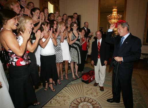 President Bush is applauded by members of the University of Georgia women's swimming and diving team, as he prepares put on the team hat Tuesday, July 12, 2005 at The White House, as part of ceremonies honoring the 2004 and 2005 NCAA Sport Championship teams. White House photo by Eric Draper