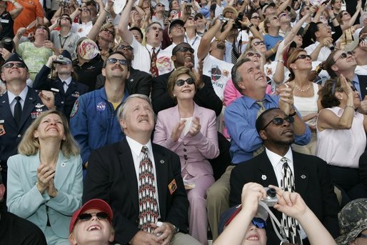 Laura Bush applauds as she folllows the launch of the Space Shuttle Discovery, Tuesday, July 26, 2005, at the Kennedy Space Center in Cape Canaveral, Florida. Mrs. Bush is joined by Florida Governor Jeb Bush, right, and NASA Astronaut Scott Altman, left. White House photo by Krisanne Johnson