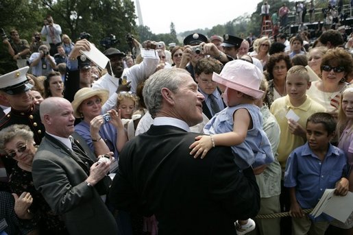 President George W. Bush holds Keira Corrigan of Mineola, N.Y., as he meets some of the hundreds of family and friends who gathered on the South Lawn of the White House, Friday, Sept. 9, 2005, during the 9/11 Heroes Medal of Valor Award Ceremony, in honor of the courage and commitment of emergency services personnel who died on Sept. 11, 2001. White House photo by Eric Draper