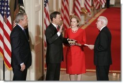 President George W. Bush watches Thursday, Sept. 29, 2005 in the East Room of the White House in Washington, as Judge John G. Roberts is sworn-in as the 17th Chief Justice of the United States by Associated Supreme Court Justice John Paul Stevens. Judge Roberts' wife Jane is seen holding the Bible.  White House photo by Paul Morse