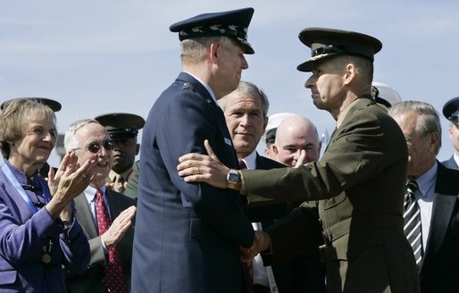 General Richard B. Myers, left, and General Peter Pace shake hands Friday, Sept. 30, 2005, during The Armed Forces Farewell Tribute in Honor of General Myers and the Armed Forces Hail in Honor of General Pace at Fort Myer's Summerall Field in Ft. Myer, Va., with Mary Jo Myers and President George W. Bush looking on. White House photo by Paul Morse