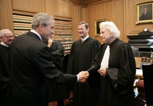 President George W. Bush shakes hands with U.S. Supreme Court Associate Justice Sandra Day O' Connor, during his visit to the U.S. Supreme Court for the investiture ceremony for U.S. Chief Justice John Roberts, seen background-center, Monday, Oct. 3, 2005 in Washington. Associate Justice John Paul Stevens is seen at left. White House photo by Eric Draper