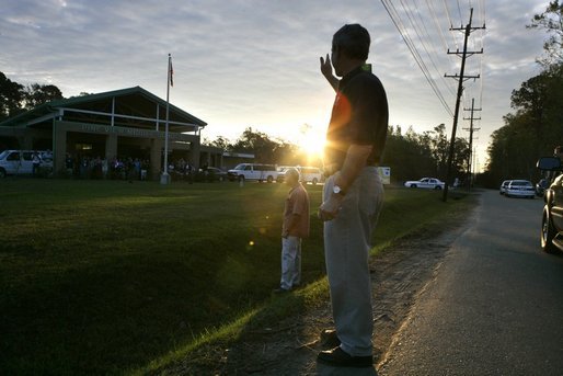 As the sun rises, President George W. Bush waves to the staff at Pine View Middle School Tuesday, Oct. 11, 2005, in Covington, La., where earlier he and Laura Bush joined a corps of Habitat for Humanity volunteers. White House photo by Eric Draper