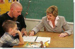 Laura Bush works with a child and father, while participating in the R.E.A.D. to Kids Training Program at J.S. Chick Elementary School in Kansas City, Mo., Tuesday, October 11, 2005.  White House photo by Krisanne Johnson