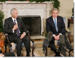 President George W. Bush is joined by Samir Sumaidaie, Iraq Ambassador to the United Nations, in the Oval Office Friday, Dec. 16, 2005. The Ambassador holds up his finger, dyed purple to signify his vote yesterday in his country's parliamentary elections.  White House photo by Paul Morse