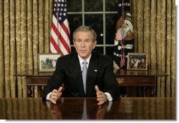 President George W. Bush addresses the nation Sunday, Dec. 18, 2005, from the Oval Office of the White House. Said the President, "Next week, Americans will gather to celebrate Christmas and Hanukkah. Many families will be praying for loved ones spending this season far from home in Iraq, Afghanistan or other dangerous places. Our Nation joins in those prayers. We pray for the safety and strength of our troops." White House photo by Eric Draper