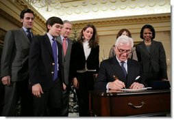 President George W. Bush stands by as John Danilovich signs appointment affidavits after being sworn in Tuesday, Dec. 20, 2005, as the new Chief Executive Officer of the Millennium Challenge Corporation during ceremonies at the U.S. Department of State. Looking on are Secretary of State Condoleezza Rice and members of Mr. Danilovich's family.  White House photo by Paul Morse