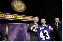 President George W. Bush receives a Kansas State Football jersey from University President Jon Wefald, center, with Kansas Senator Pat Roberts before delivering remarks on the global War on Terror at Kansas State University in Manhattan, Kan., Monday, Jan. 23, 2006. White House photo by Eric Draper