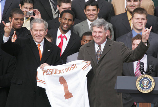 President George W. Bush holds up a University of Texas Longhorns jersey with head football coach Mack Brown, as they give the 'Hook Em Horns' sign, Tuesday, Feb. 14, 2006 on the South Lawn of the White House, during ceremonies to honor the 2005 NCAA Football Champions. White House photo by Paul Morse