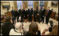 President George W. Bush and the crew members of the Space Shuttle Discovery (STS-114) pose for news photographers in the Oval Office at the White House, Wednesday, Feb. 22, 2006. The STS-114 crew was the first U.S. Space Shuttle flight, July 26, 2005, since the February 2003 loss of the Space Shuttle Columbia. White House photo by Eric Draper