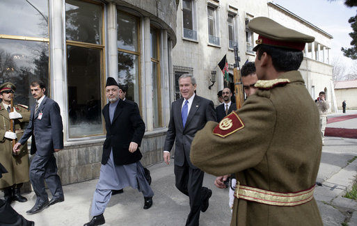 President George W. Bush is accompanied by Afghan President Hamid Karzai at the Presidential Palace in Kabul after President and Mrs. Bush landed in Afghanistan for a brief visit en route to India. During their five-hour stop, they participated in a ceremonial ribbon-cutting at the U.S. Embassy and visited with troops at Bagram Air Base north of the city. White House photo by Eric Draper