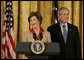 President George W. Bush listens on as Mrs. Laura Bush welcomes women leaders to the East Room for a celebration Tuesday, March 7, 2006, of International Women's Day. Mrs. Bush said, "I've been privileged to meet thousands of women from many nations, and I believe that women everywhere share the same dreams -- to be educated, to live in peace, to enjoy good health, to be prosperous, and to be heard." White House photo by Kimberlee Hewitt