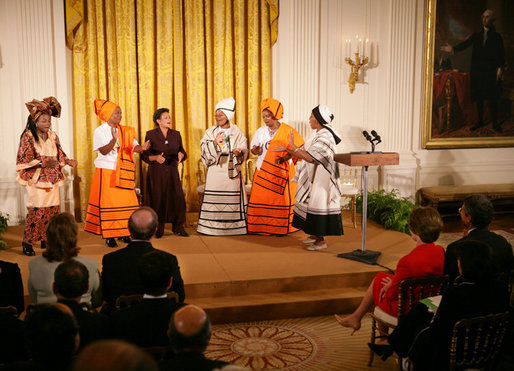 Mrs. Laura Bush listens to a performance from members of the Mothers to Mothers-To-Be representatives of South Africa, Monday, March 13, 2006 in the East Room of the White House. Mrs. Bush had earlier met with the members of the program, who mentor and counsel mothers who come for prenatal care to clinics and find they are HIV-positive, on her visit to South Africa in July of 2005. From left to right on stage are Aunt Manyongo "Kunene" Mosima Tantoh, Nosisi Mngceke, Patty Thomas, Gloria Ncanywa, Monica Abdullah and Babalwa Mbono. White House photo by Shealah Craighead