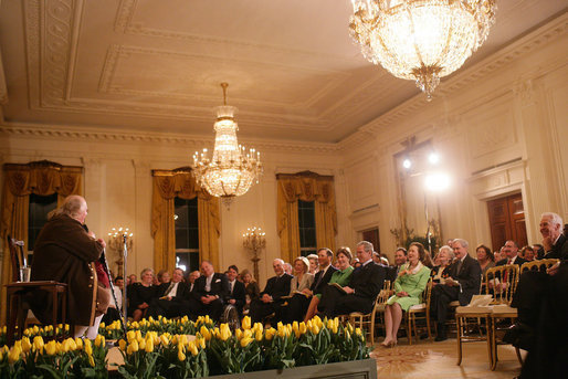 President George W. Bush and Mrs. Laura Bush join their invited guests in listening to Benjamin Franklin interpreter, Ralph Archbold of Philadelphia, Pa., Thursday evening, March 23, 2006 in the East Room of the White House, during a Social Dinner to honor the 300th birthday of Benjamin Franklin. White House photo by Shealah Craighead