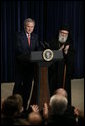 President George W. Bush is applauded by Archbishop Demetrios from the Greek Orthodox Church of America, Friday, March 24, 2006 at the Eisenhower Executive Office Building in Washington, where President Bush addressed an audience celebrating Greek Independence Day and honored the 185th anniversary of Greece's Independence. White House photo by Eric Draper