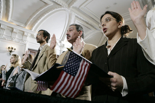 Naturalization ceremony participants raise their hands and hold American flags as they are sworn-in as new U.S. citizens Monday, March 27, 2006, during the Naturalization Ceremony at the Daughters of the American Revolution Administration Building in Washington. President George W.Bush addressed the audience, saying that each generation of immigrants brings a renewal to our national character and adds vitality to our culture. White House photo by Eric Draper