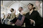 Naturalization ceremony participants raise their hands and hold American flags as they are sworn-in as new U.S. citizens Monday, March 27, 2006, during the Naturalization Ceremony at the Daughters of the American Revolution Administration Building in Washington. President George W.Bush addressed the audience, saying that each generation of immigrants brings a renewal to our national character and adds vitality to our culture. White House photo by Eric Draper