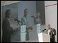 President George W. Bush addresses the media as Mexico's President Vicente Fox and Canadian Prime Minister Stephen Harper are seen on a large video screen listening during their joint news conference, Friday, March 31, 2006 at the Fiesta Americana Condesa Cancun Hotel in Cancun, Mexico. White House photo by Eric Draper