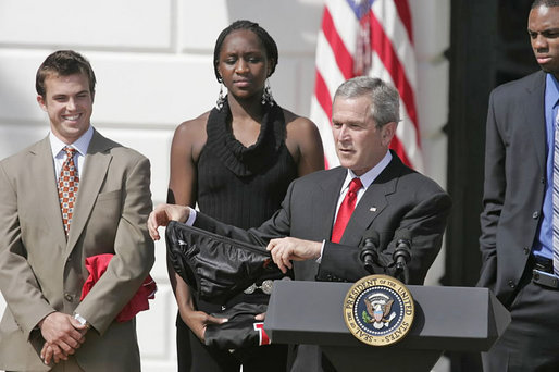 President George W. Bush holds up his gift from the Auburn's Swimming and Dving Teams during his remarks congratulating the NCAA Championship Teams on the South Lawn Thursday, April 6, 2006. "Coach David Marsh is with us, both the men's swimming and diving teams earned national championships," said the President. " That's rare to do. And I welcome both teams with us today. It kind of says that, in a year of swimming, this is the year of War Eagle. I want you all to know that the women's swimming team kindly brought me a -- (laughter) -- awfully thoughtful of you. I'm not going to wear it." White House photo by Paul Morse