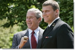 President George W. Bush sports an oversized championship ring as the stands with Midshipman Jeremy Chase of the United States Naval Academy football team during the presentation of the Commander-in-Chief Trophy to in the Rose Lawn April 25, 2006. White House photo by Paul Morse