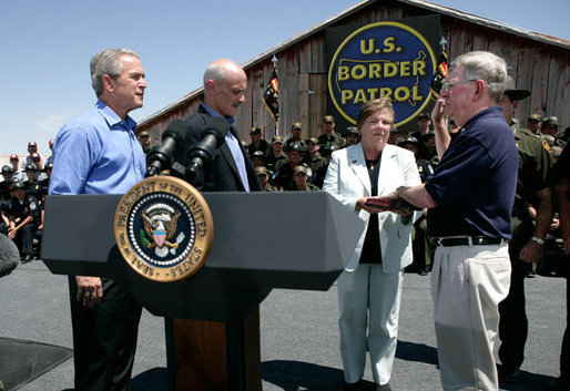 President George W. Bush stands with U.S.Homeland Security Secretary Michael Chertoff during the swearing-in ceremony of W. Ralph Basham, right, as the new Commissioner for U.S. Customs and Border Protection, Tuesday, June 6, 2006 at the Federal Law Enforcement Training Center Artesia Facility in Artesia, New Mexico. Commissioner Basham's wife, Judy Basham, holds the Bible during the ceremony. White House photo by Eric Draper