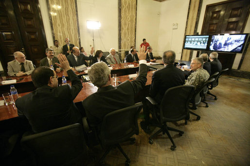 From Baghdad, President George W. Bush and Prime Minister Nouri al-Maliki of Iraq, wave to Vice President Dick Cheney, Secretary of State Condoleezza Rice and Secretary of Defense Donald Rumsfeld in Camp David, Md., during a teleconference Tuesday, June 13, 2006. White House photo by Eric Draper