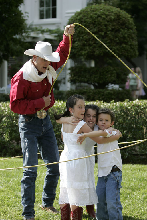  A rope trick cowboy lassos three children on the South Lawn of the White House as part of the entertainment at the annual Congressional Picnic Wednesday evening, June 15, 2006. White House photo by Kimberlee Hewitt