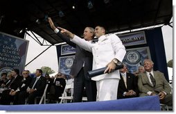 President George W. Bush waves to the audience with a recent graduate during the graduation ceremony at the United States Merchant Marine Academy at Kings Point, New York, Monday, June 19, 2006. White House photo by Kimberlee Hewitt