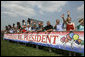 Standing behind a banner wishing President George W. Bush a happy birthday a crowd waves to President Bush, who celebrated his 60th birthday Thursday, as he departs from Chicago, Friday, July 7, 2006. White House photo by Eric Draper