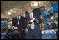 President George W. Bush holds up red, white and blue shoes presented to him by CEO John Stollenwerk during his visit to the Allen-Edmonds Shoe Corporation in Port Washington, Wis., Tuesday, July 11, 2006. White House photo by Kimberlee Hewitt