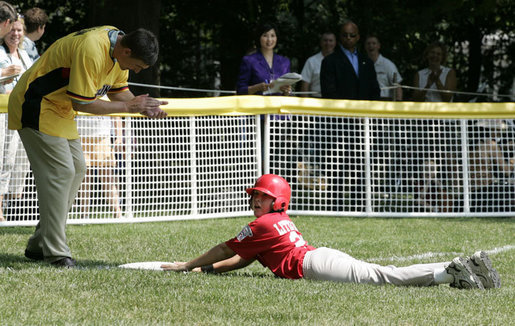 A member of the Thurmont Little League Civitan Club of Frederick Challengers of Thurmont, Md., is applauded by third base coach Dan Wilson as he slides into third base Sunday, July 30, 2006, at the White House Tee Ball on the South Lawn game against the Shady Spring Little League Challenger Braves of Shady Spring W. Va. White House photo by Paul Morse