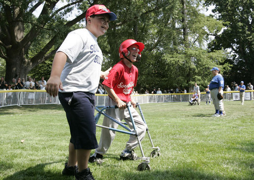 A player for the Thurmont Little League Civitan Club of Frederick Challengers of Thurmont, Md., is accompanied to first base by a South Lawn buddy Sunday, July 30, 2006, at the White House Tee Ball on the South Lawn game against the Shady Spring Little League Challenger Braves of Shady Spring W. Va. White House photo by Paul Morse