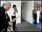 President George W. Bush stands with Polly Noble as they listen Tuesday, Aug. 29, 2006, to J.D. Hill on his harmonica and guitarist Charlie Moore during a visit to Musicians' Village in New Orleans' 9th Ward. The President and Laura Bush hosted a lunch with volunteers from Habitat for Humanity in appreciation of their work on the site for displaced New Orleans musicians. White House photo by Eric Draper