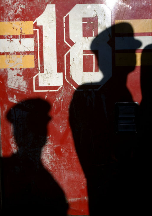 Shadows from New York City First Responders are cast upon a door of Ladder 18, one of the fire trucks destroyed in the September 11th terrorist attacks, during a moment of silence at the Fort Pitt Firehouse in New York City Monday, September 11, 2006. White House photo by Kimberlee Hewitt