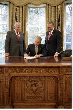 President George W. Bush signs S. 418, The Military Personnel Financial Services Protection Act, in the Oval Office Friday, Sept. 29, 2006. Standing with President Bush are bill sponsors Senator Mike Enzi, R-Wyo., left and Representative Geoff Davis, R-Ky. The legislation protects America’s armed forces by banning unscrupulous companies from military bases. It also prohibits the selling of life insurance products military personnel and their dependents unless specified written disclosures have been provided. White House photo by Eric Draper