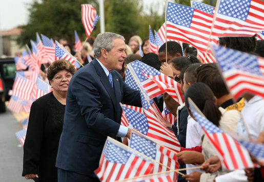 President George W. Bush reaches into a flurry of flags to greet students at George W. Bush Elementary School in Stockton, Calif., Tuesday, Oct. 3, 2006. White House photo by Eric Draper