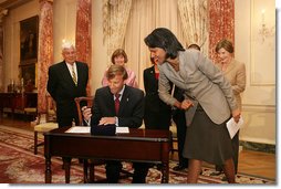 Mrs. Laura Bush, along with family of Ambassador Mark Dybul, watch as U.S. Secretary of State Condoleezza Rice assists newly sworn-in Ambassador Mark Dybul as he signs appointment documents Tuesday, October 10, 2006, during the swearing-in ceremony of Ambassador Mark Dybul in the Benjamin Franklin Room at the U.S. Department of State in Washington, D.C.  White House photo by Shealah Craighead