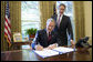 With Sen. Bill Frist (R-Tenn.) looking on, President George W. Bush signs into law S. 3728, the North Korea Nonproliferation Act of 2006, Friday, Oct. 13, 2006, in the Oval Office. White House photo by Eric Draper