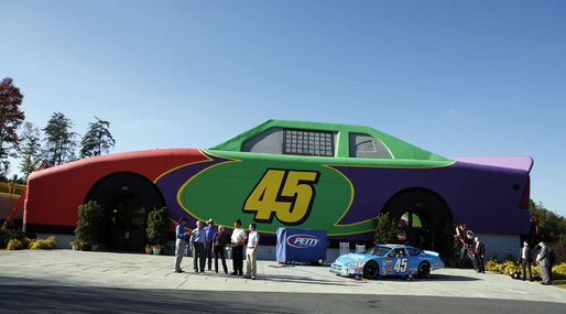 President George W. Bush, second from left, is joined at Adam's Race Shop on the grounds of Victory Junction Gang Camp, Inc., in Randleman, N.C., by NASCAR drivers, from left: Kyle Petty, Richard Petty, Michael Waltrip and Jimmie Johnson. Pattie Petty, who founded the camp for kids with chronic conditions with husband Kyle, is at center. White House photo by Paul Morse