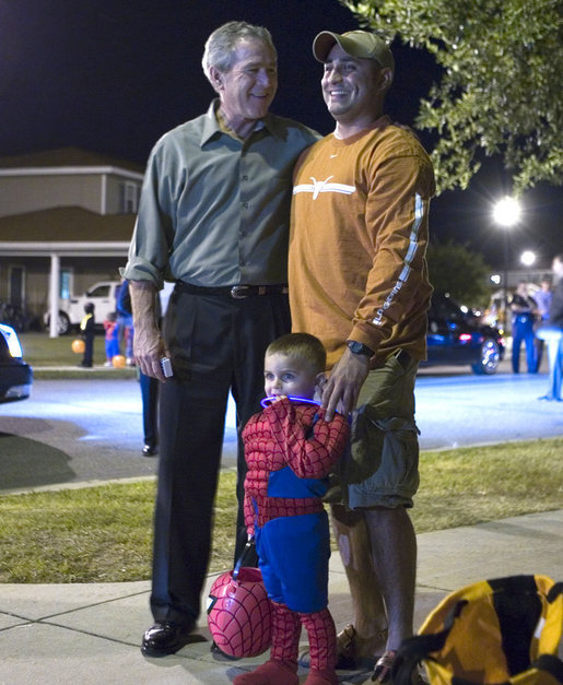 President George W. Bush poses for photos with a University of Texas fan and Spiderman Tuesday, Oct. 31, 2006, during a stop at a housing area at Robins Air Force Base, Ga. The President passed out M&Ms to the trick-or-treaters before his return to Washington, D.C. White House photo by Paul Morse