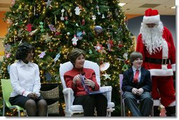 Mrs. Laura Bush sits with patient escorts Allison Meads, left, and Matthew Morgan, as she reads to an audience of children, patients and hospital staff Friday, Dec. 8, 2006, at The Children's National Medical Center in Washington, D.C., where Mrs. Bush visited with patients and debuted the 2006 Barney Cam video. White House photo by Shealah Craighead