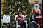 Mrs. Laura Bush sits with patient escorts Allison Meads, left, and Matthew Morgan, as she reads to an audience of children, patients and hospital staff Friday, Dec. 8, 2006, at The Children's National Medical Center in Washington, D.C., where Mrs. Bush visited with patients and debuted the 2006 Barney Cam video. White House photo by Shealah Craighead