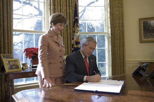 Laura Bush stands by President George W. Bush as he signs H.R. 6143, the Ryan White HIV/AIDS Treatment Modernization Act of 2006, in the Oval Office Tuesday, Dec. 19, 2006. White House photo by Eric Draper