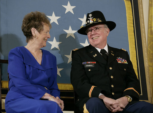 U.S. Army Major Bruce P. Crandall sits with his wife, Arlene, before a banner of the Medal of Honor in the East Room of the White House, Monday, Feb. 26, 2007, prior to Crandall being awarded the Medal of Honor for his extraordinary heroism as a 1st Cavalry helicopter flight commander in the Republic of Vietnam in November 1965. White House photo by Eric Draper