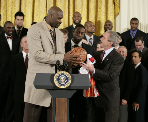 President George W. Bush receives an autographed ball from Shaquille O'Neal Tuesday, Feb. 27, 2007, as the 2006 NBA champions visited the White House. The President told the East Room audience he was most impressed by the Heat's work in their Miami community and added, "I mean, I'm in awe of their athletic skills. Standing next to Shaq is an awe-inspiring experience." White House photo by Eric Draper