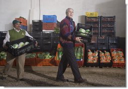 President George W. Bush wearing a Hupile, a handmade, traditional jacket, lends a hand loading crates of lettuce Monday, March 12, 2007, during a visit to the Labradores Mayas Packing Station in Chirijuyu, Guatemala. The jacket was presented to him earlier in the day by the director of the Dr. Richard Carroll Library in Santa Cruz Balanya.  White House photo by Paul Morse