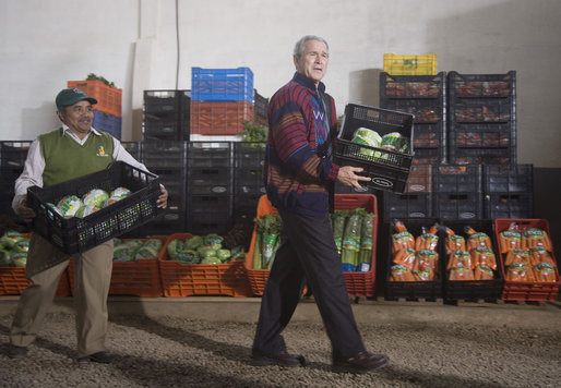 President George W. Bush wearing a Hupile, a handmade, traditional jacket, lends a hand loading crates of lettuce Monday, March 12, 2007, during a visit to the Labradores Mayas Packing Station in Chirijuyu, Guatemala. The jacket was presented to him earlier in the day by the director of the Dr. Richard Carroll Library in Santa Cruz Balanya. White House photo by Paul Morse