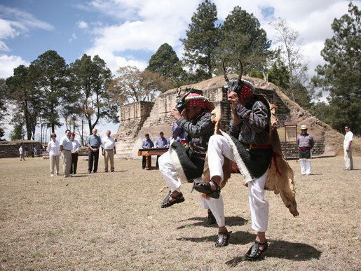 Members of the Patzun Dance group perform a cultural dance Monday, March 12, 2007, during a visit to Iximche, Guatemala, by President George W. Bush and Mrs. Laura Bush and President Oscar Berger of Guatemala and his wife, Mrs. Wendy Widmann de Berger, who look on in the background. White House photo by Paul Morse